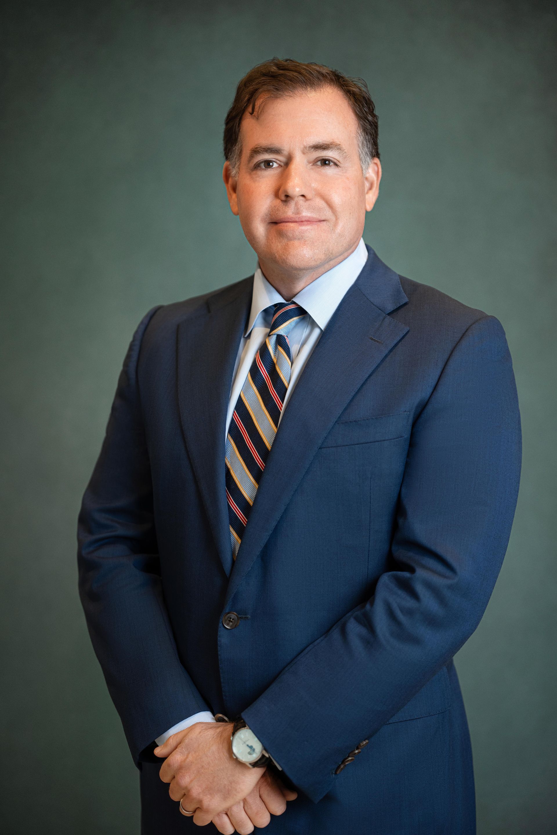 Woman in graduation cap and gown, smiling, outdoors on a wooden walkway.