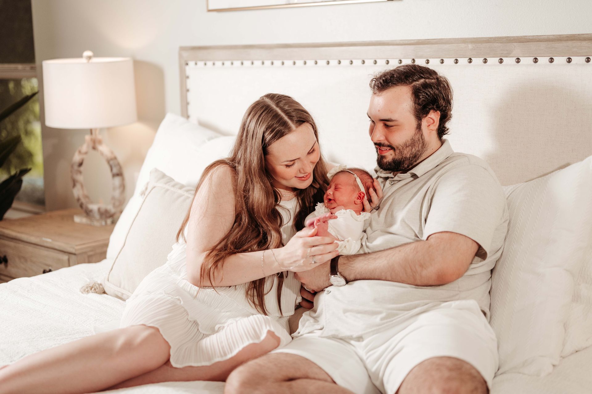 Parents in a bedroom, smiling and holding newborn baby.