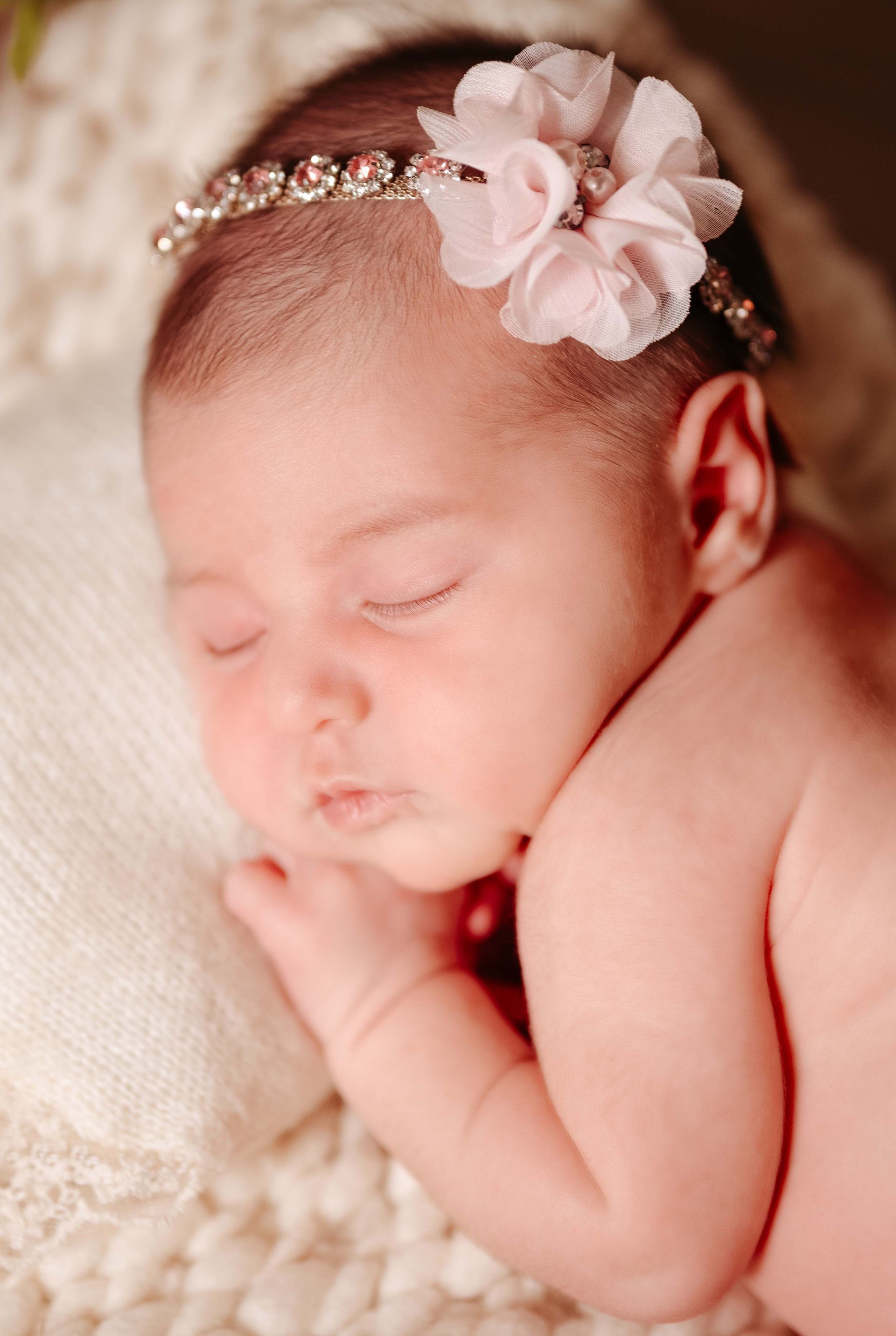 Sleeping newborn with pink floral and jeweled headband.