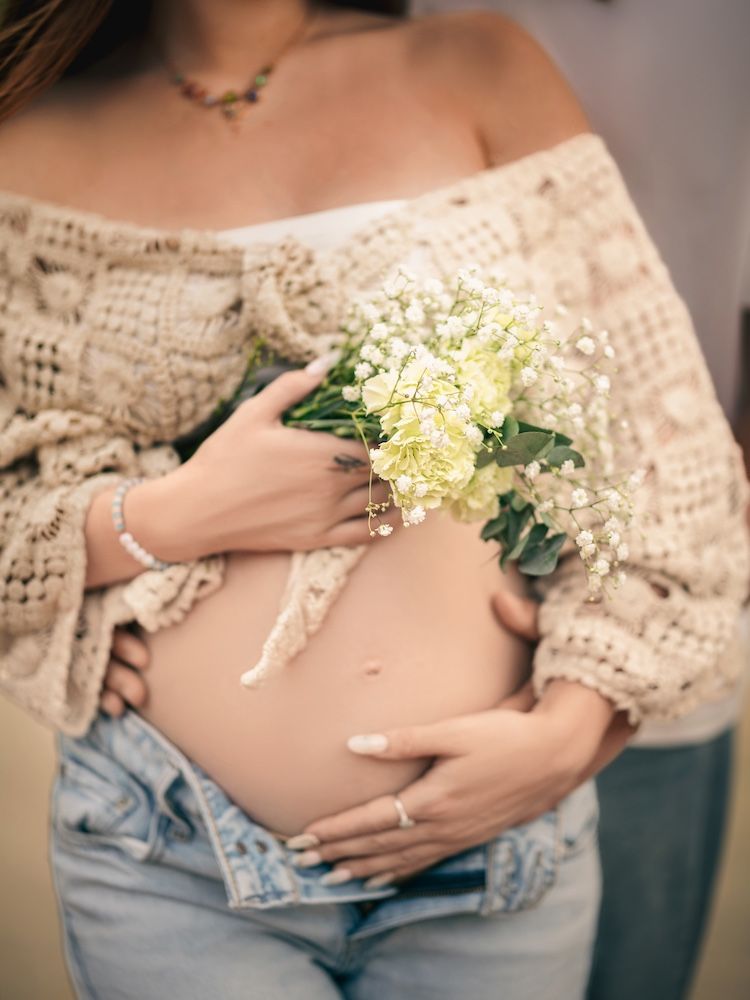 Woman in blue dress talking on phone, working on laptop outside cafe.