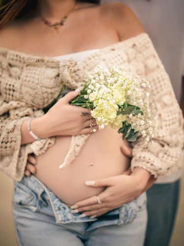 Woman in blue dress talking on phone, working on laptop outside cafe.