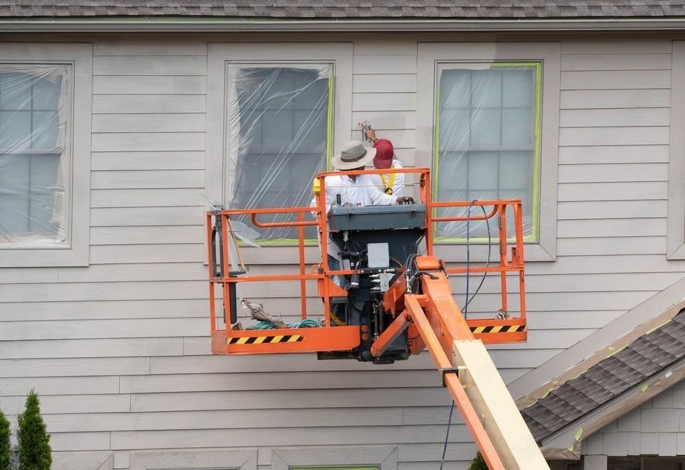 two men are painting the side of a house .