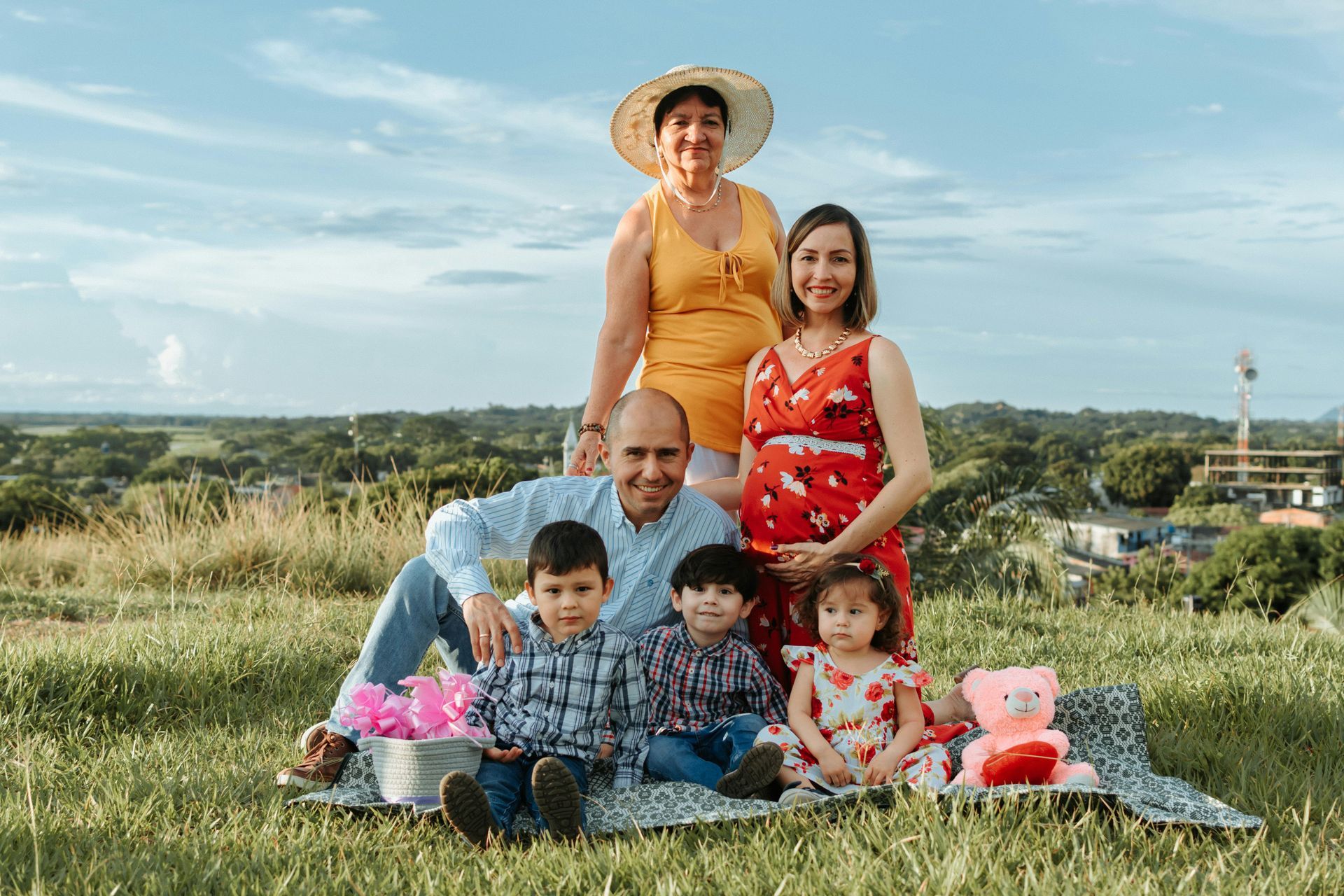 A family is posing for a picture while sitting on a blanket in the grass.