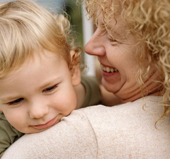A woman with curly hair is holding a small child