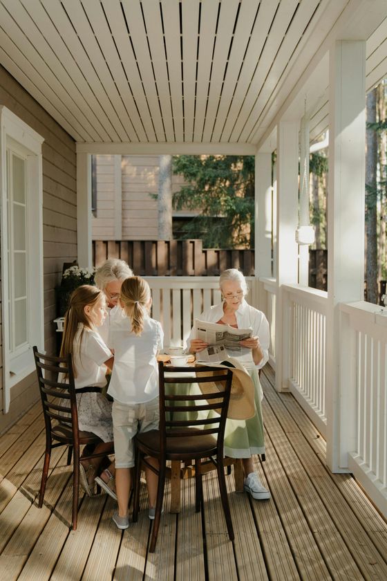 A group of people are sitting at a table on a porch.