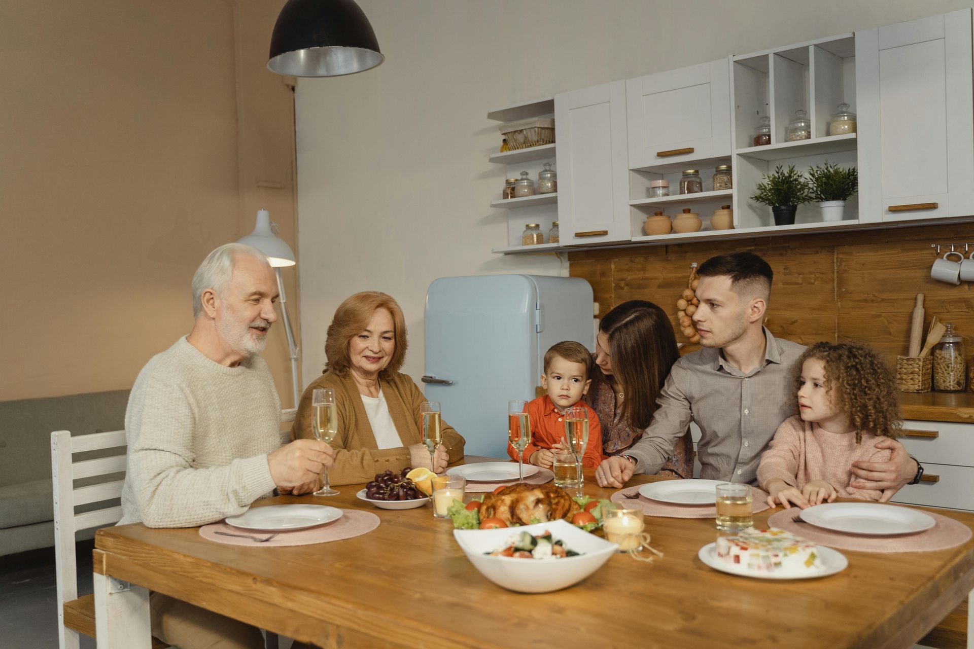 Family gathered at a dining table in a kitchen. They are eating and talking together.