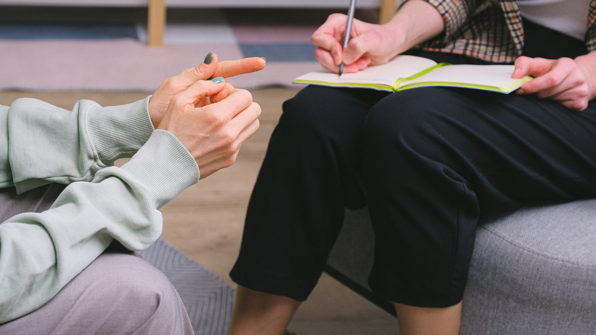 A man is sitting at a table with a clipboard in front of a couple sitting on a couch.