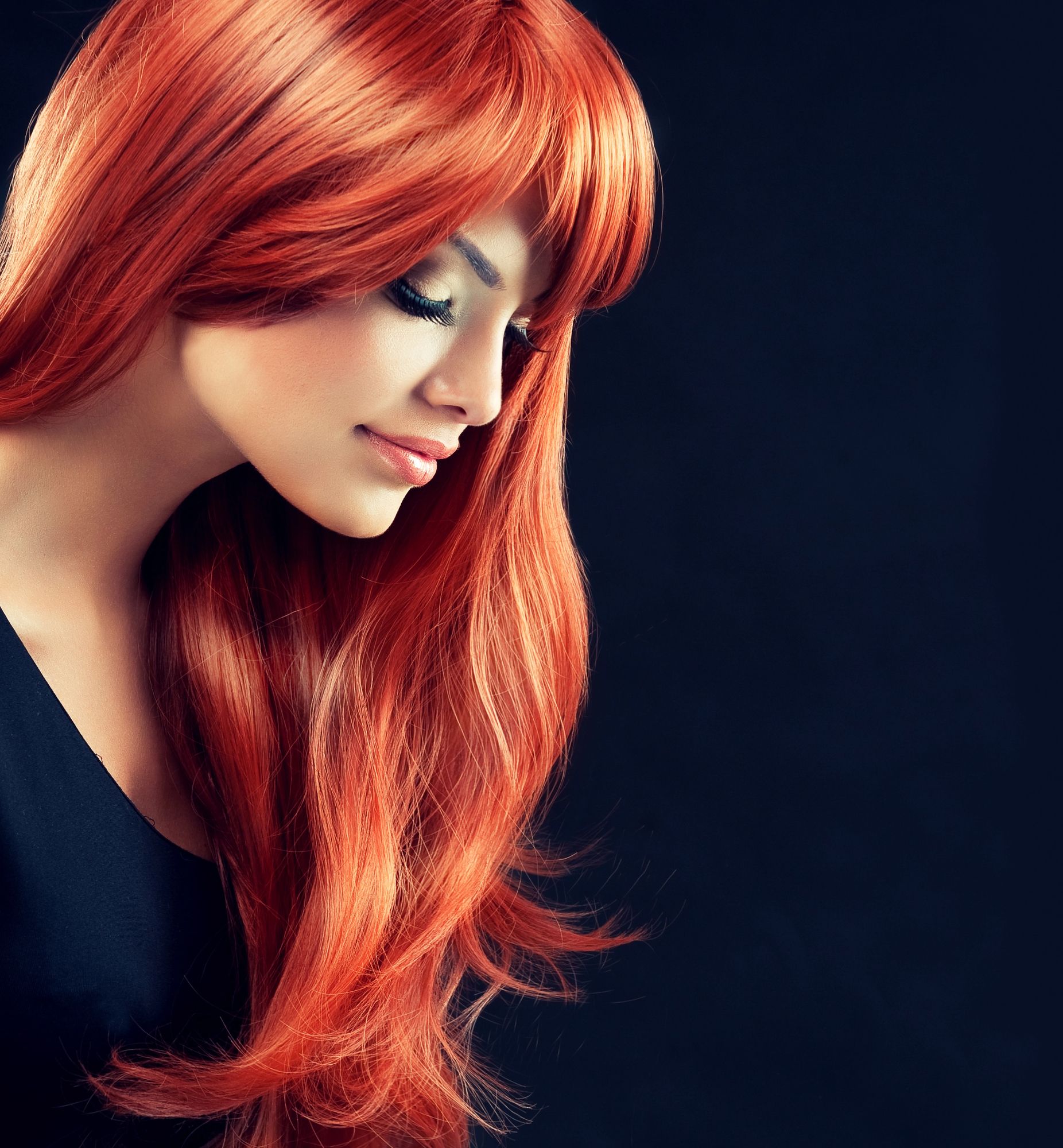 Vista de perfil de una persona con cabello largo, rojo intenso y flequillo