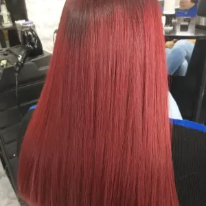 Una persona con cabello largo, liso y de color rojo brillante en una peluquería.