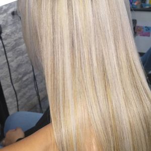 Primer plano de cabello liso con mechas rubias que muestra una mezcla de tonos platino claro y castaño dorado más cálido.