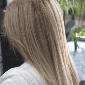 Cabello liso, rubio ceniza claro, a la altura de los hombros, peinado con un corte suave y capeado, visto desde atrás.