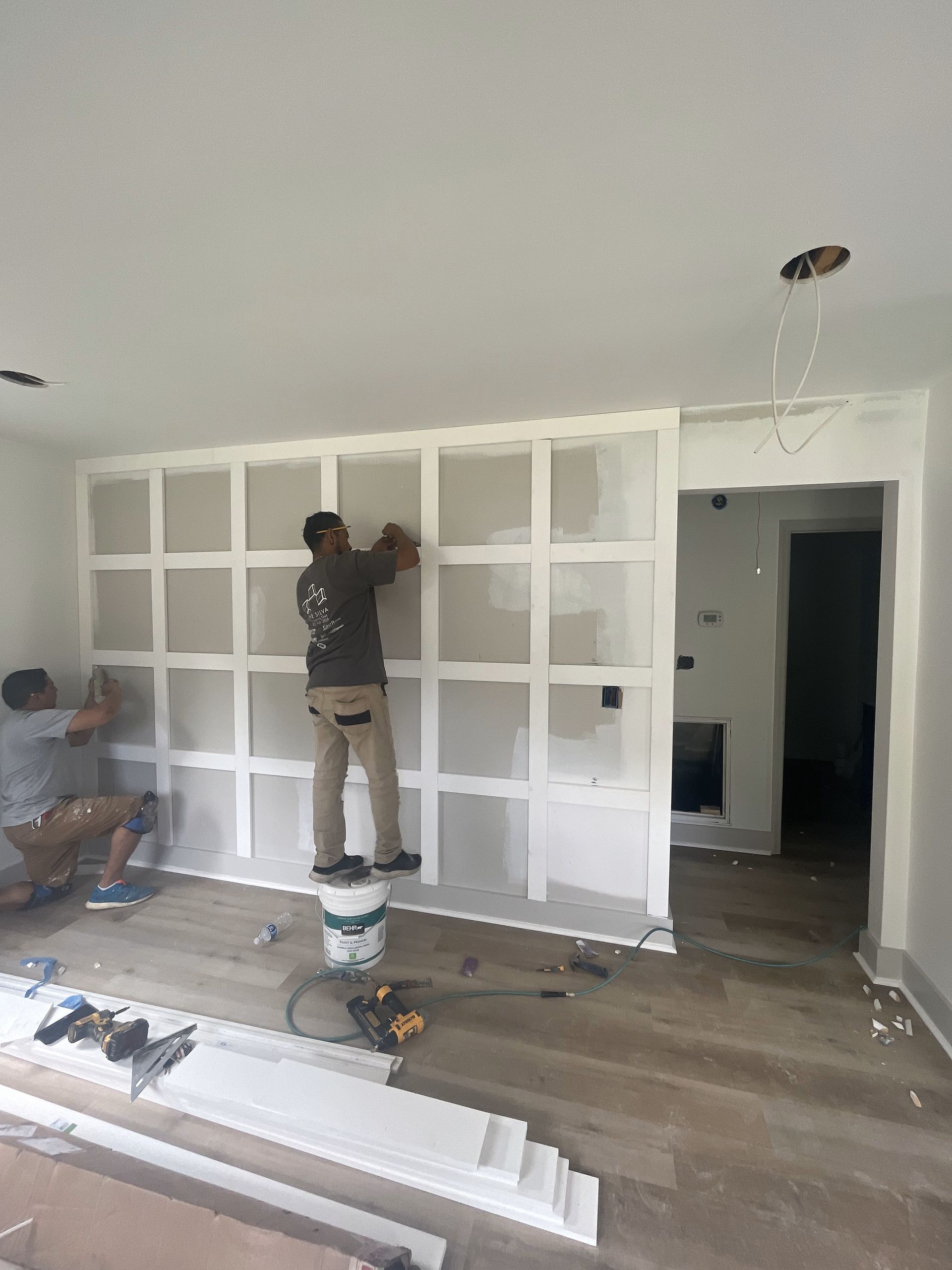 A man is working on a wall of shelves in a living room.