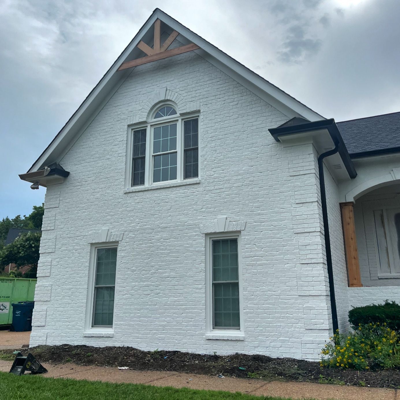 A white brick house with a roof and a lot of windows.