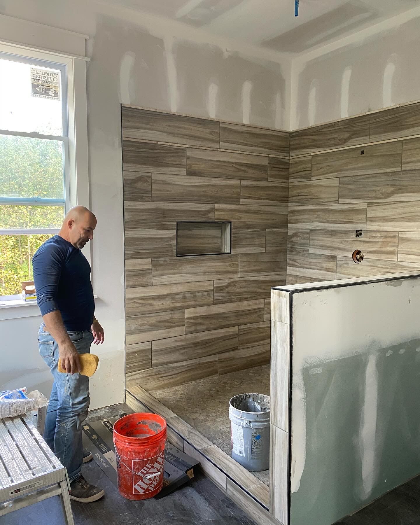 A man is standing in a bathroom under construction.