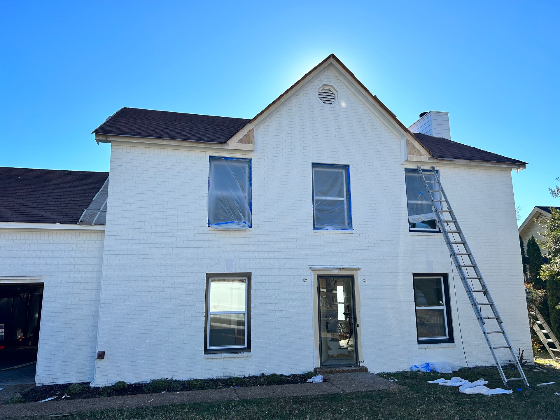 A white brick house with a ladder leaning against it