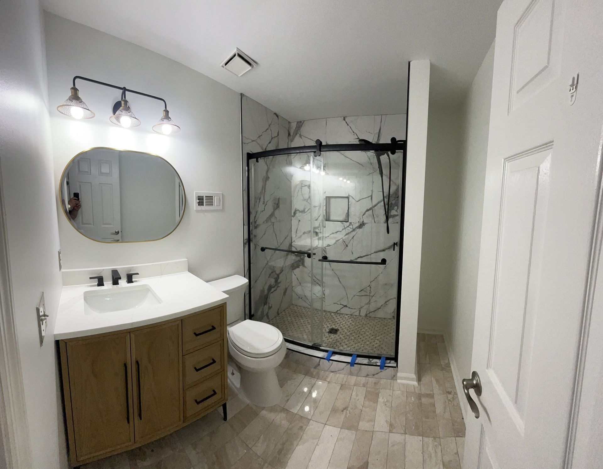 A bathroom with a sink , toilet , shower and mirror.