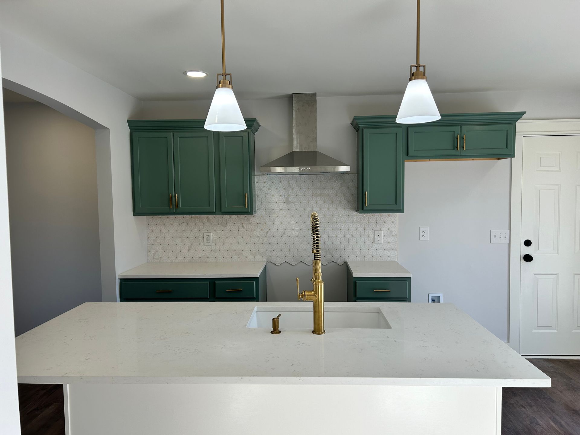 A kitchen with green cabinets and a white counter top