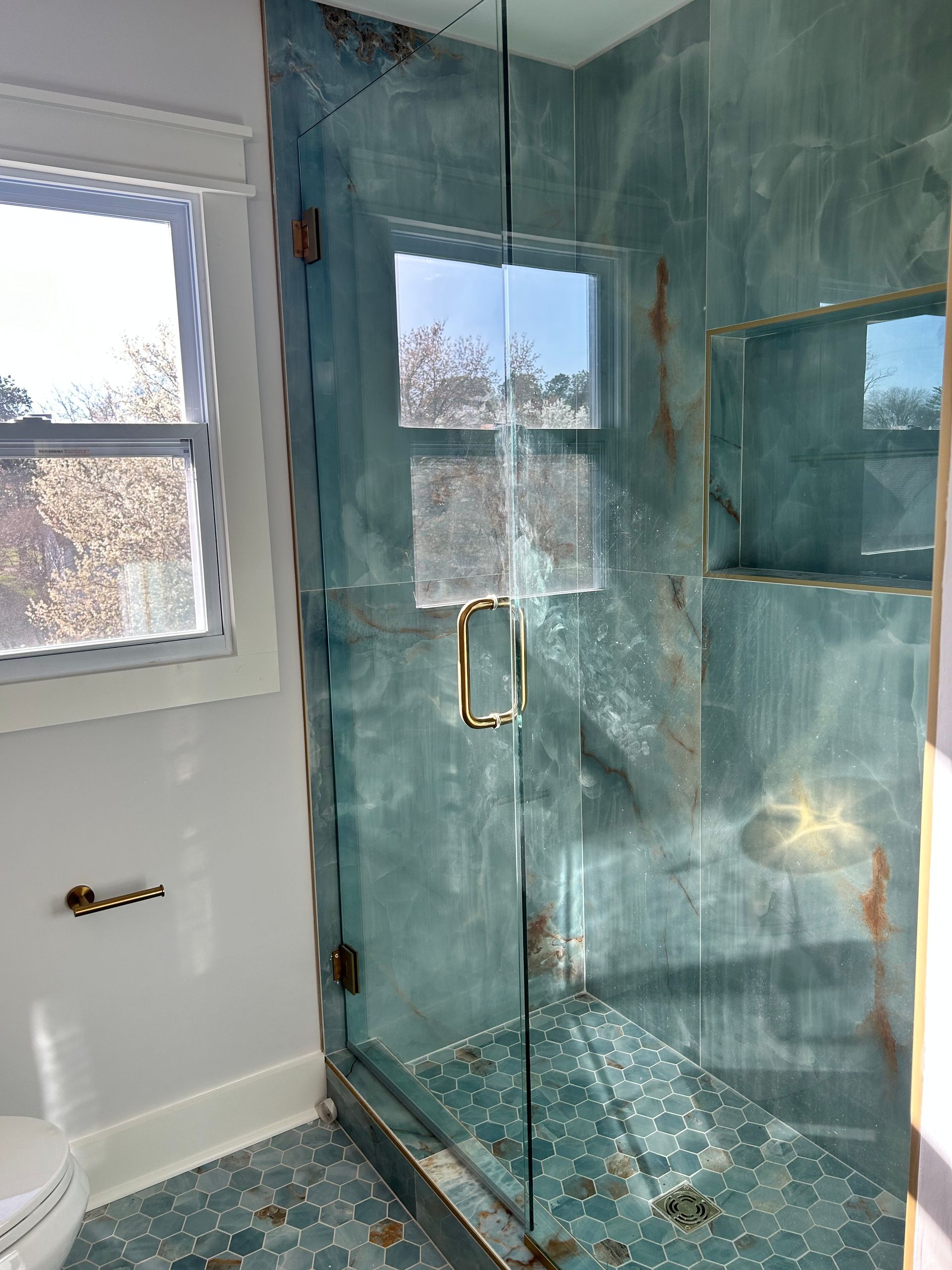 A bathroom with a glass shower door and a window.