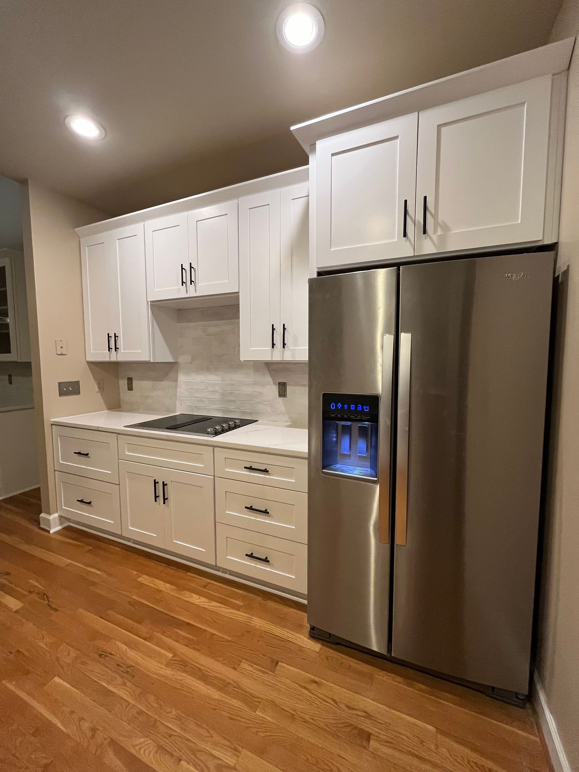 A kitchen with white cabinets and a stainless steel refrigerator
