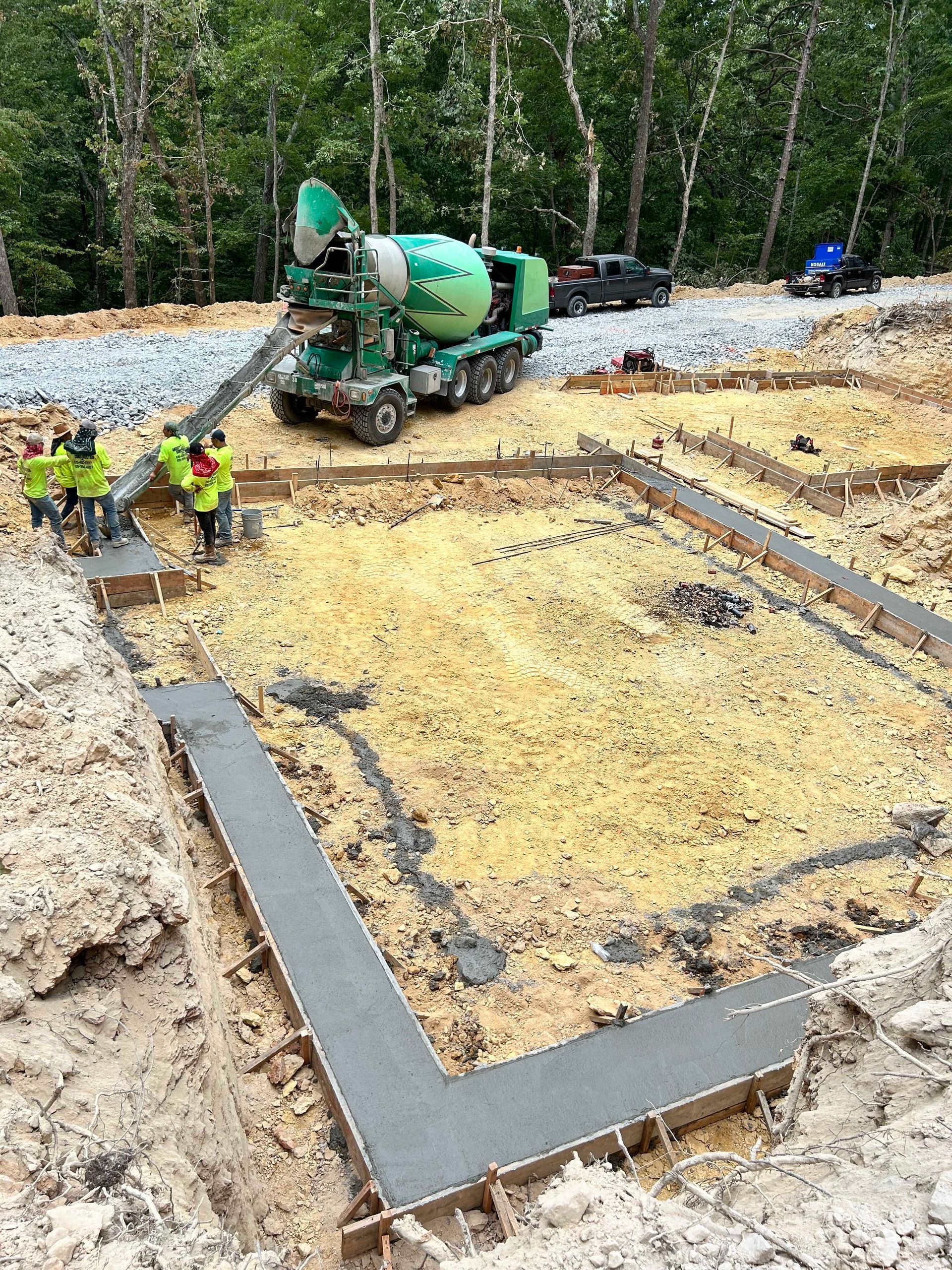 A concrete mixer is pouring concrete into a foundation at a construction site.