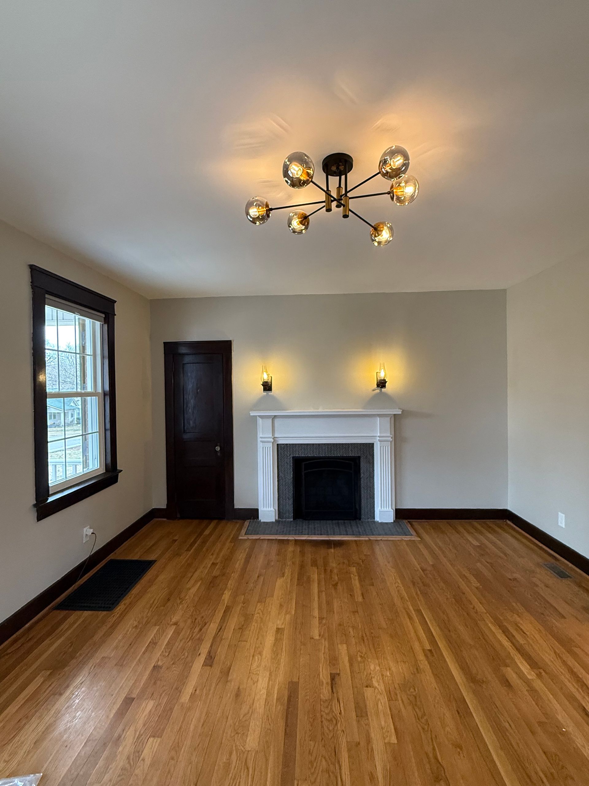 An empty living room with hardwood floors and a fireplace.