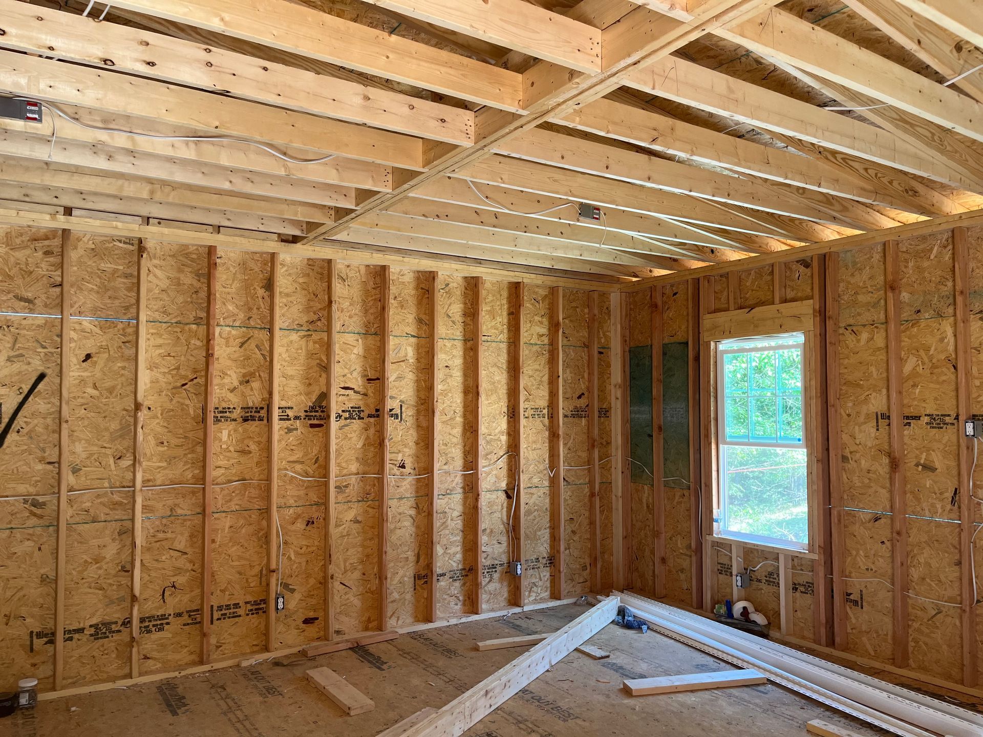A room under construction with wooden beams and a window.