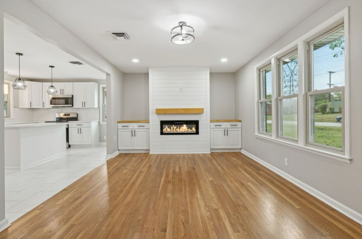 An empty living room with hardwood floors and a fireplace