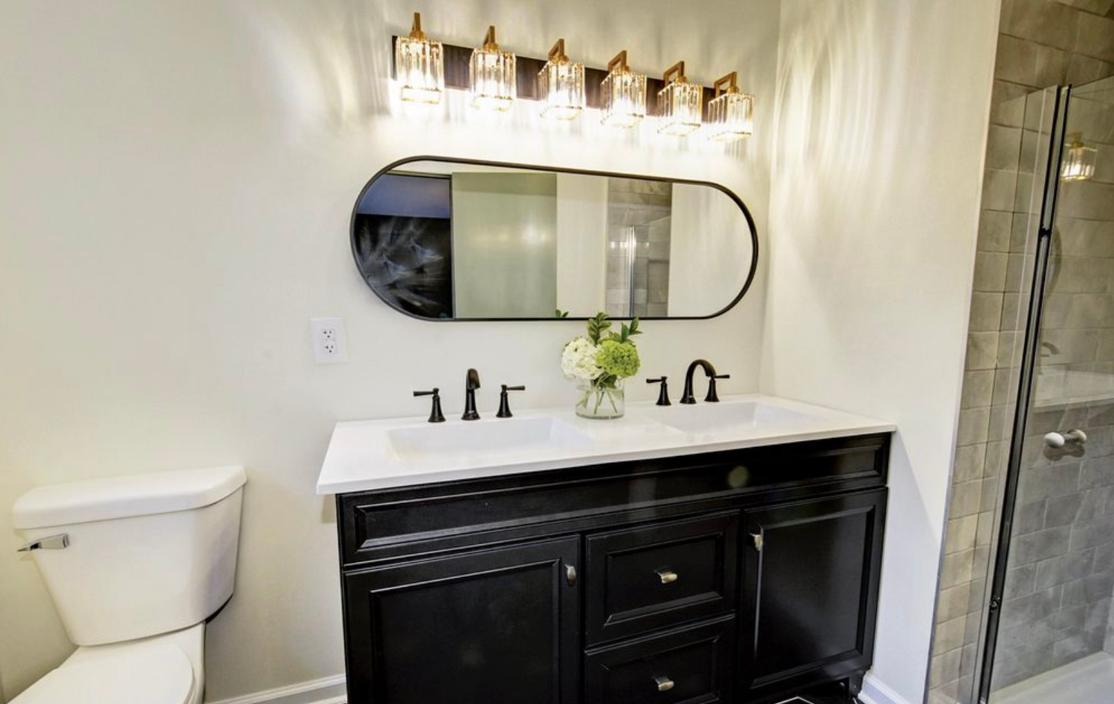 A bathroom with two sinks , a toilet and a mirror.