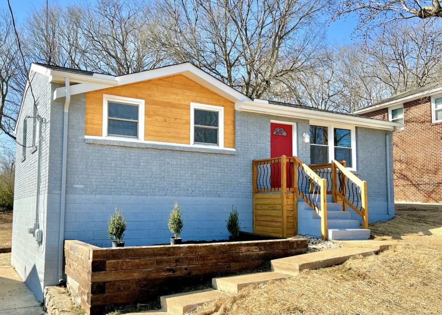 A small house with a red door and stairs in front of it.