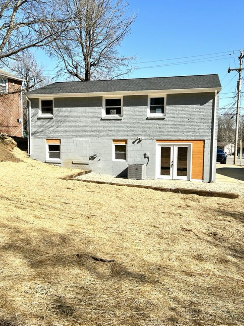 A house with a lot of windows and a lot of grass in front of it.