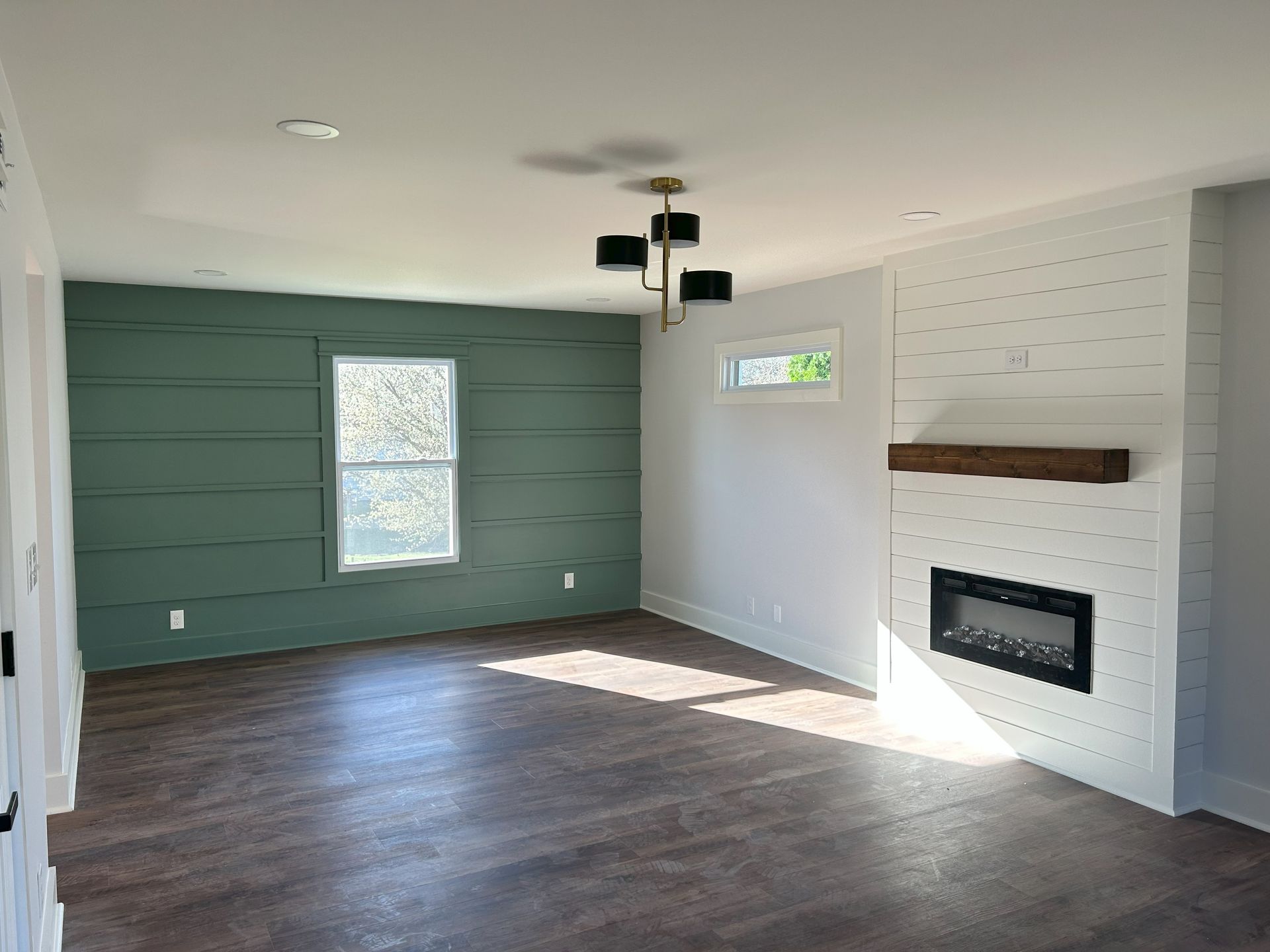 An empty living room with green walls and a fireplace.