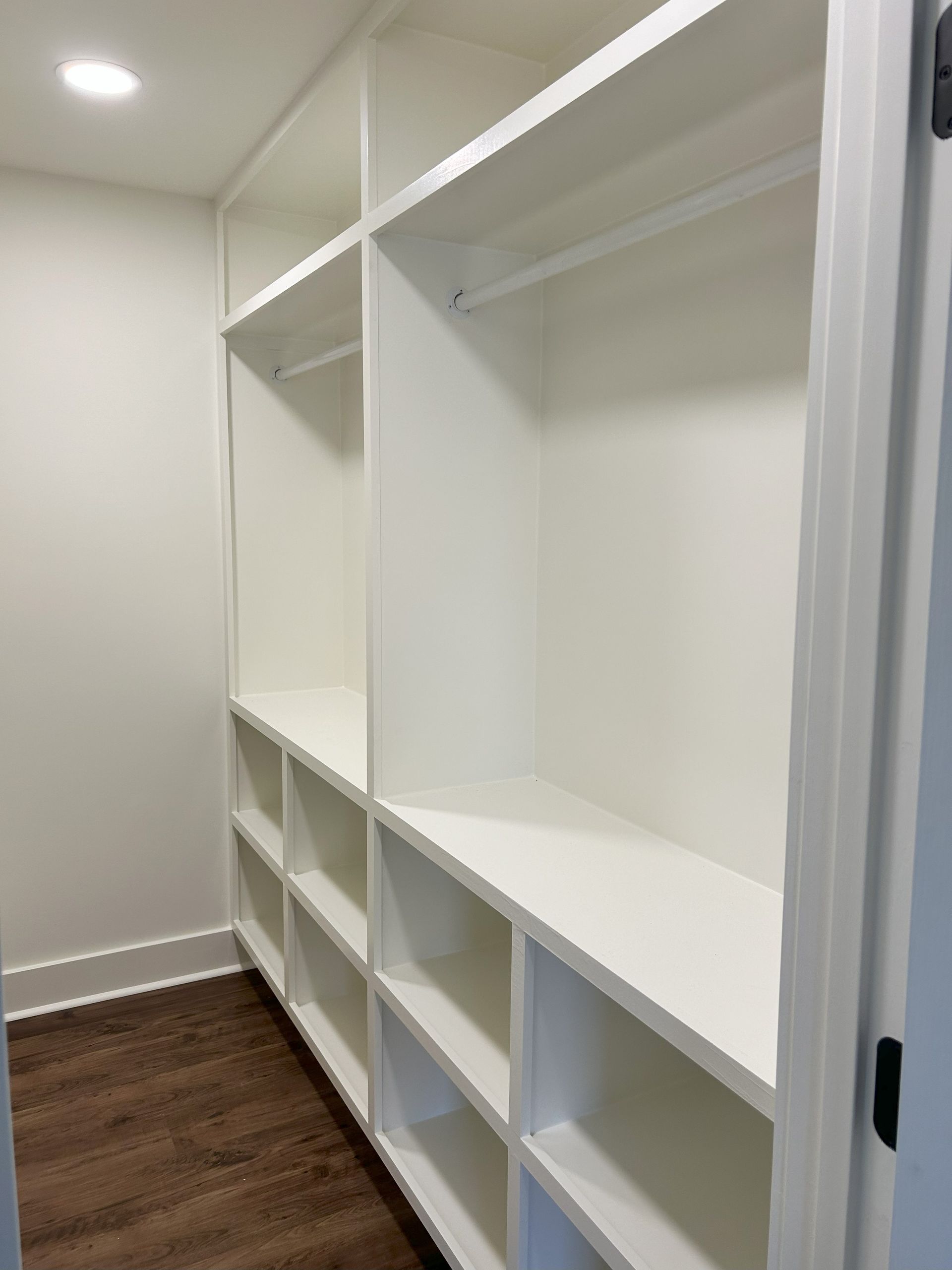 A walk in closet with lots of shelves and hanging clothes.
