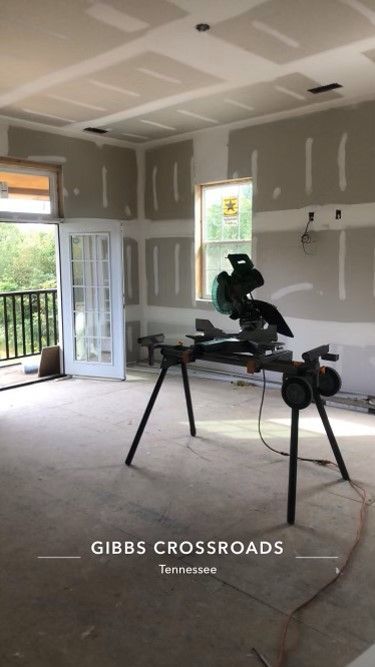 A room under construction with a circular saw on a stand.