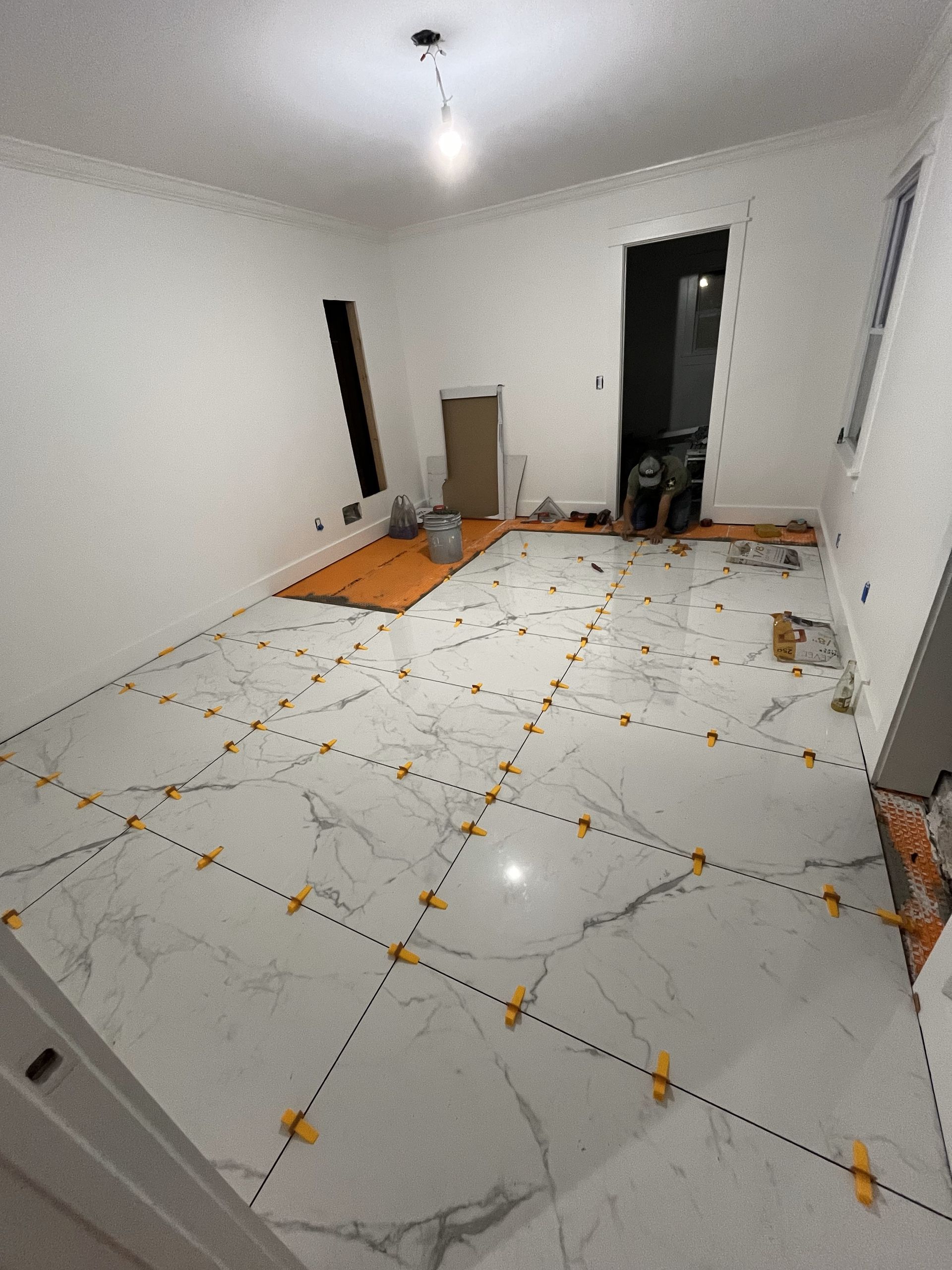 A room with a marble floor and white walls is being remodeled.