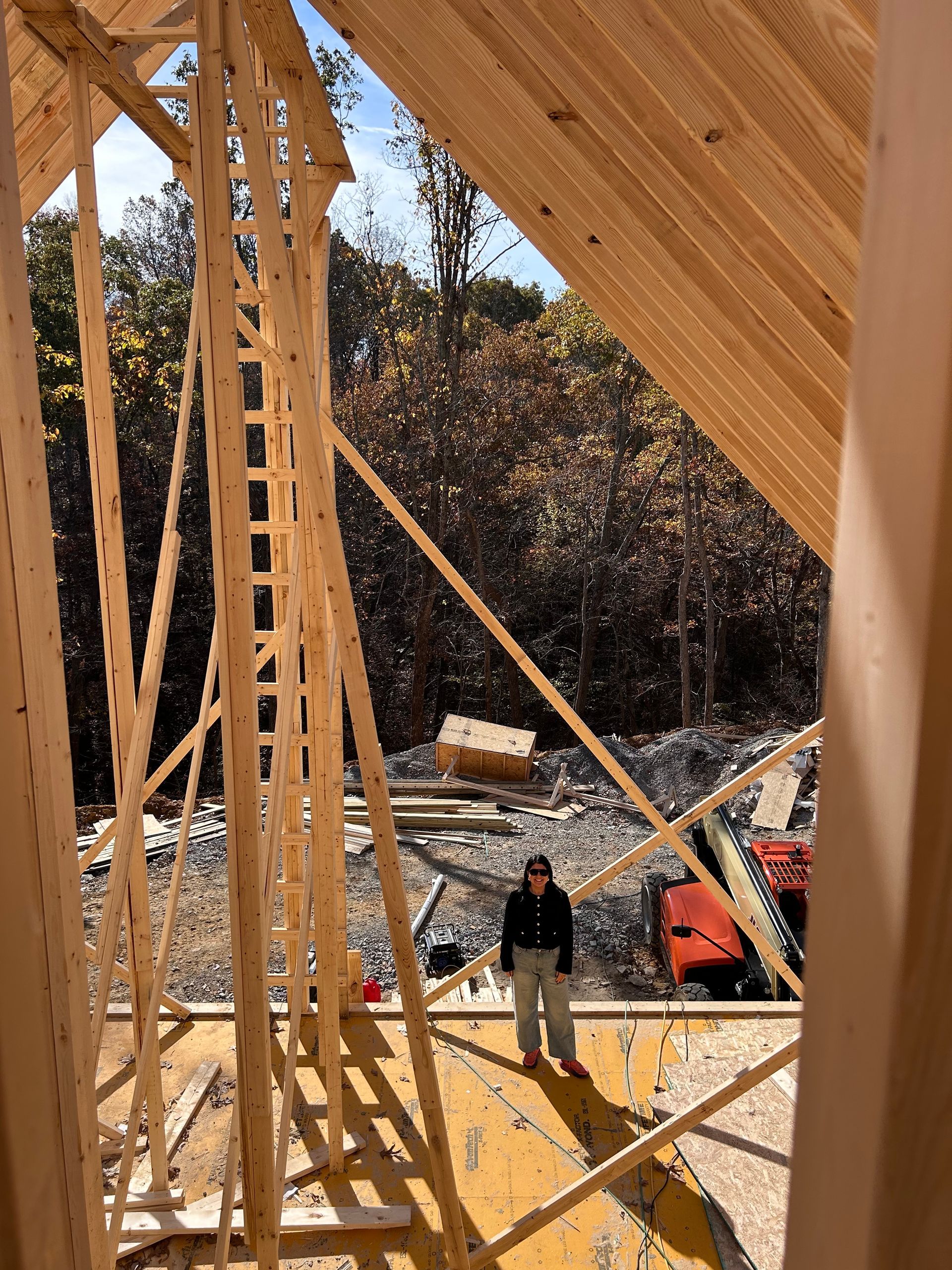 A man is standing in the middle of a wooden structure under construction.