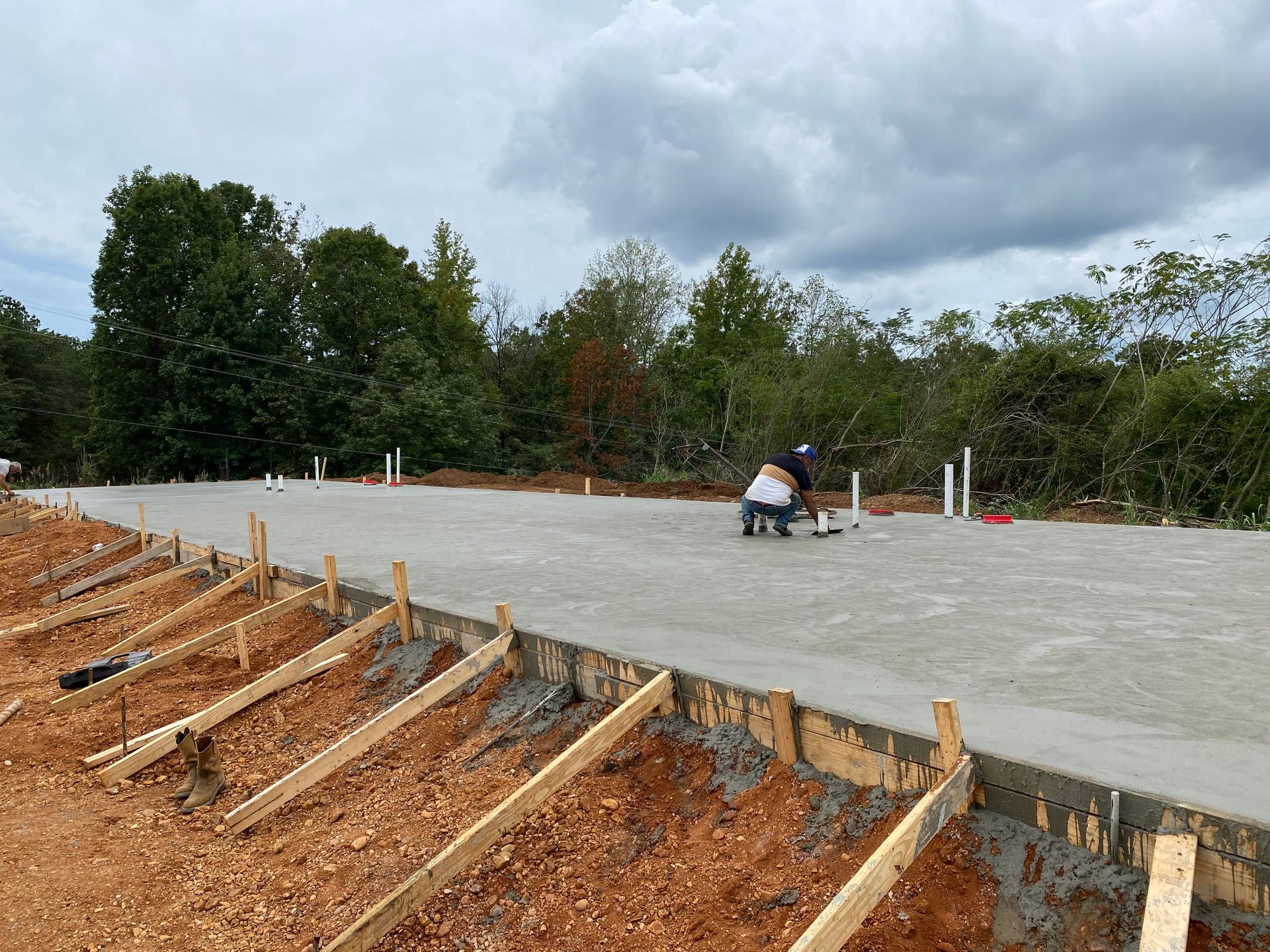 A man is working on a concrete floor in a field.
