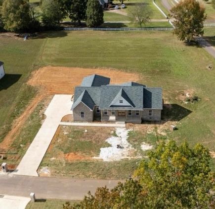 An aerial view of a house in the middle of a lush green field.