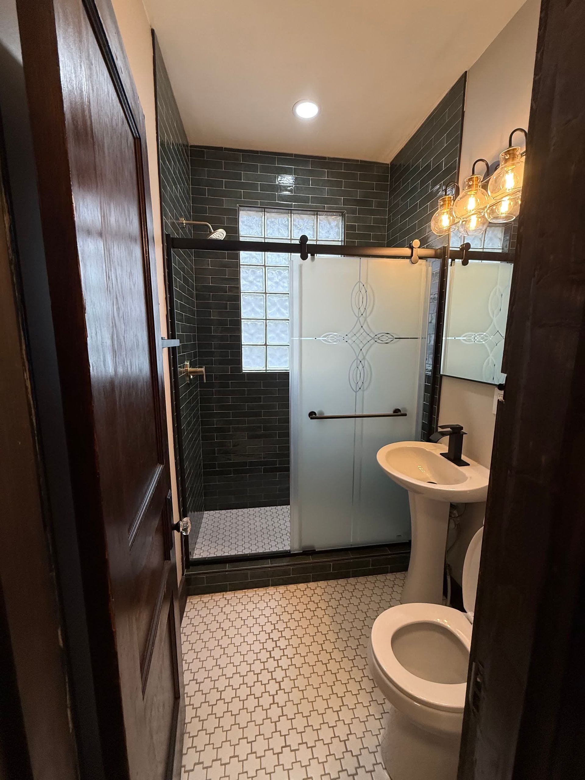 A bathroom with a toilet , sink and shower.