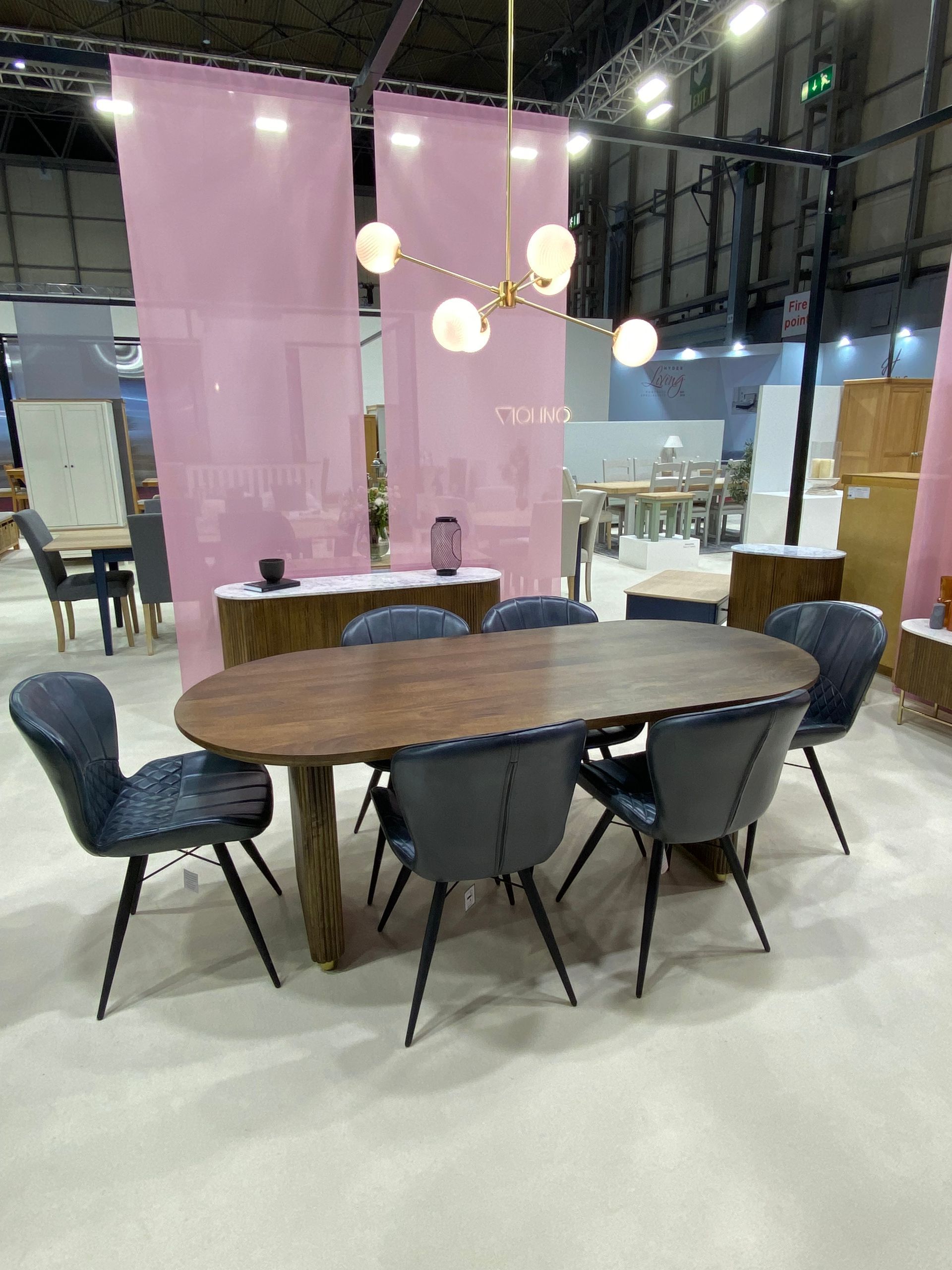a table and chairs in a dispay stand with pink curtains at the January Furniture Show 2024, NEC, Birmingham
