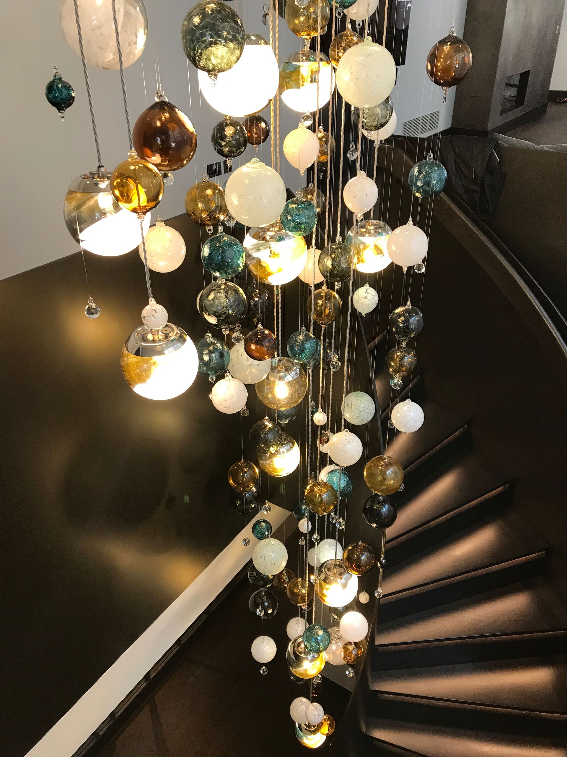 a spiral staircase with a Roast Designs chandelier hanging from the ceiling