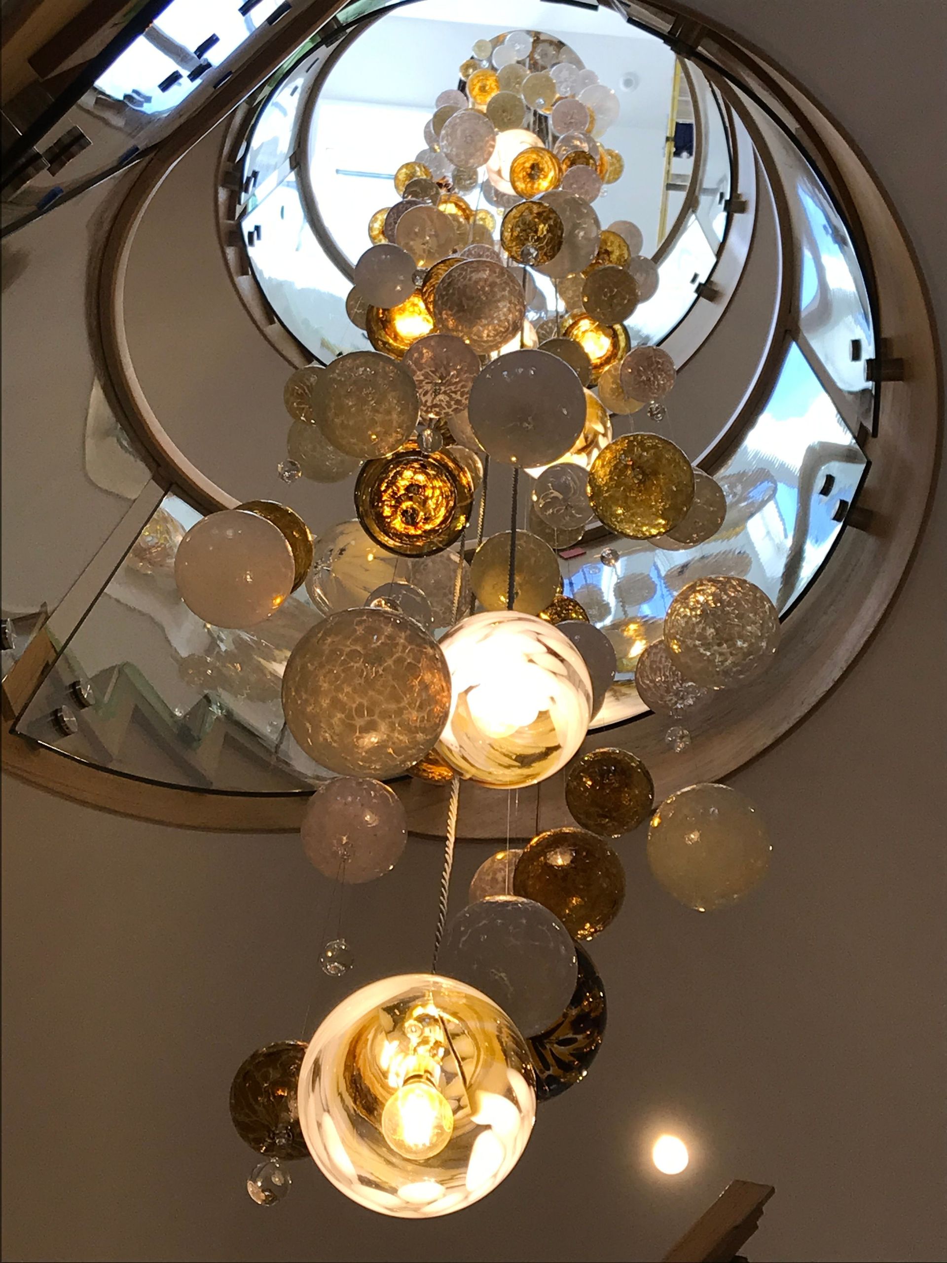 a spiral staircase with a Roast Designs gold glass ball chandelier hanging from the ceiling