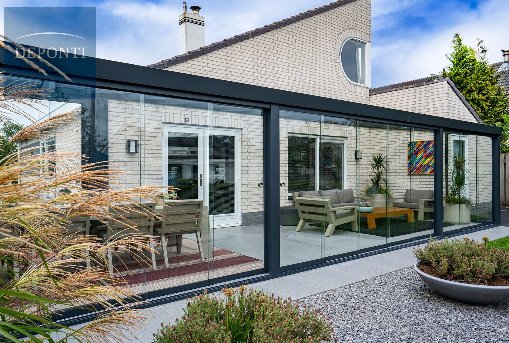 Premium Deponti aluminium veranda with glass sliding panels to the side and front and a table and chairs under the canopy