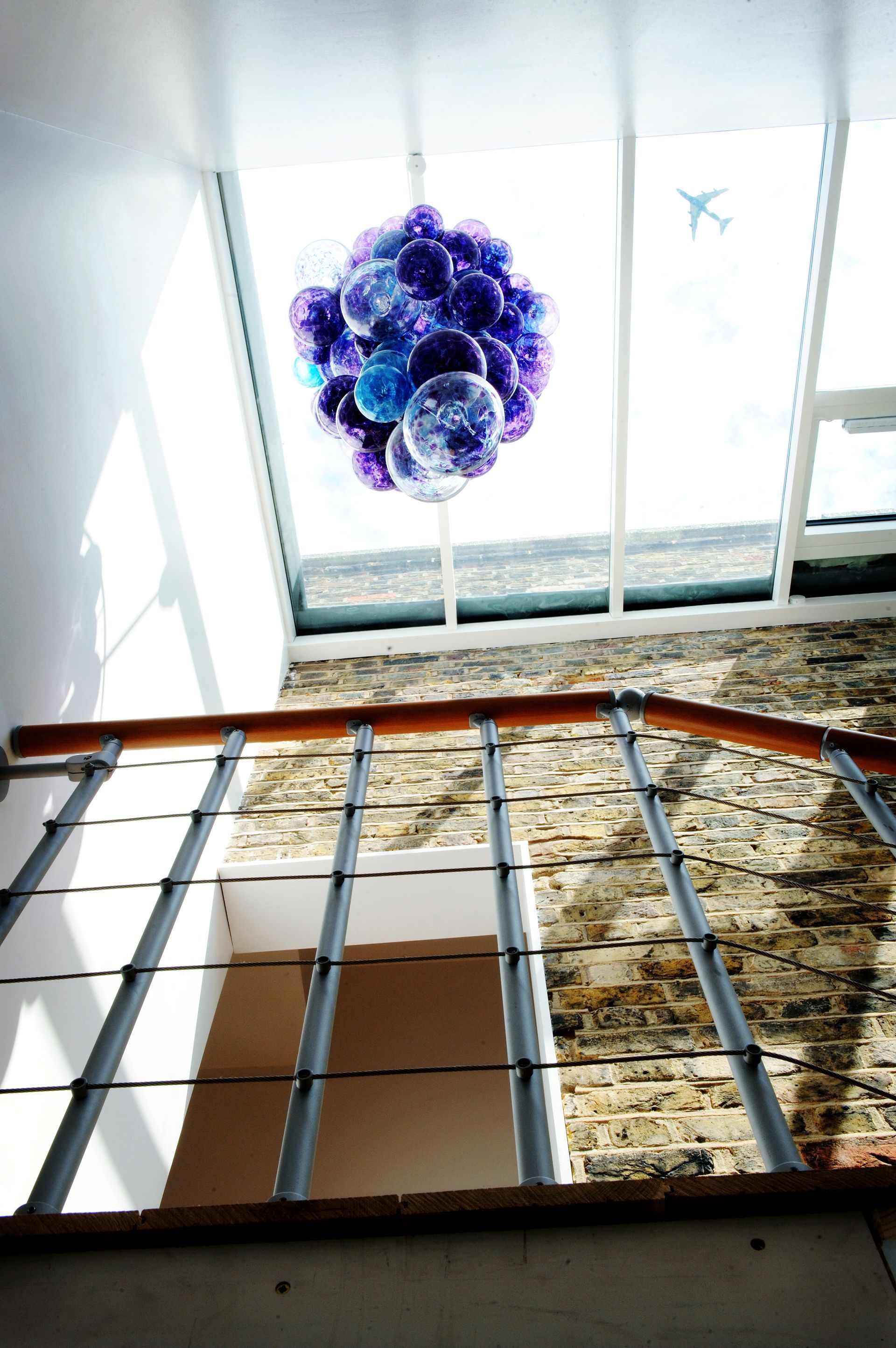 a staircase with a Roast Designs blue and purple glass balls chandelier hanging from the ceiling
