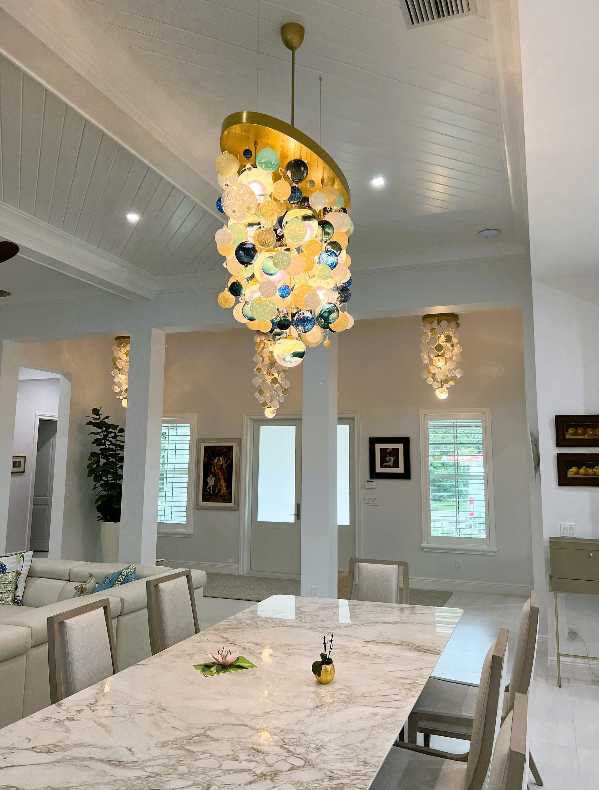 a dining room with a long table and chairs and a Roast Designs chandelier hanging from the ceiling