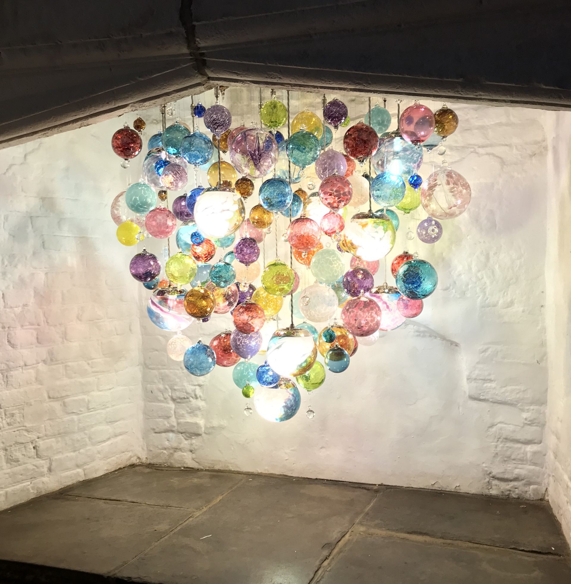 a room with a Roast Designs colorful glass ball chandelier hanging from the ceiling