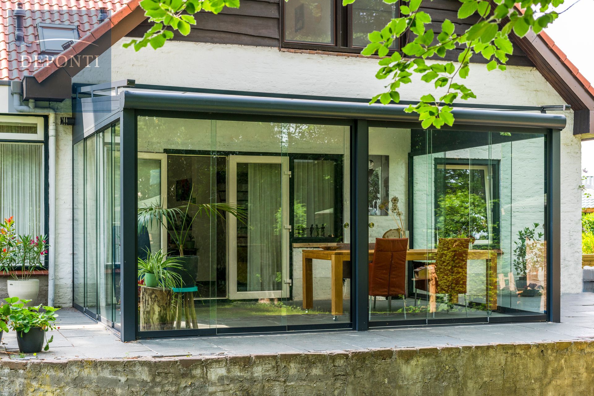 Deponti aluminium veranda with glass sliding panels to the side and front and a table and chairs under the canopy