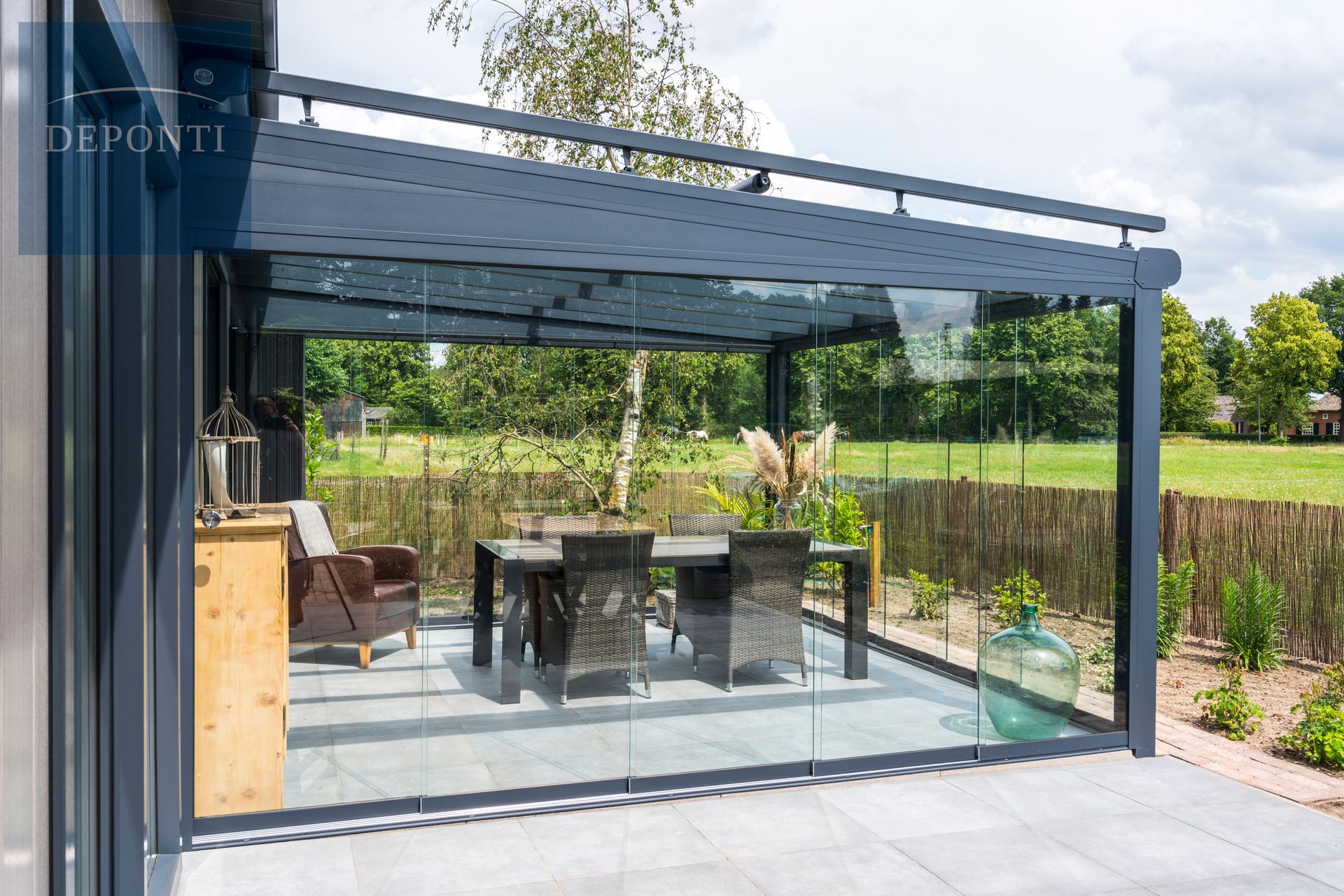 Deponti aluminium veranda with glass sliding panels to the side and front and a table and chairs under the canopy
