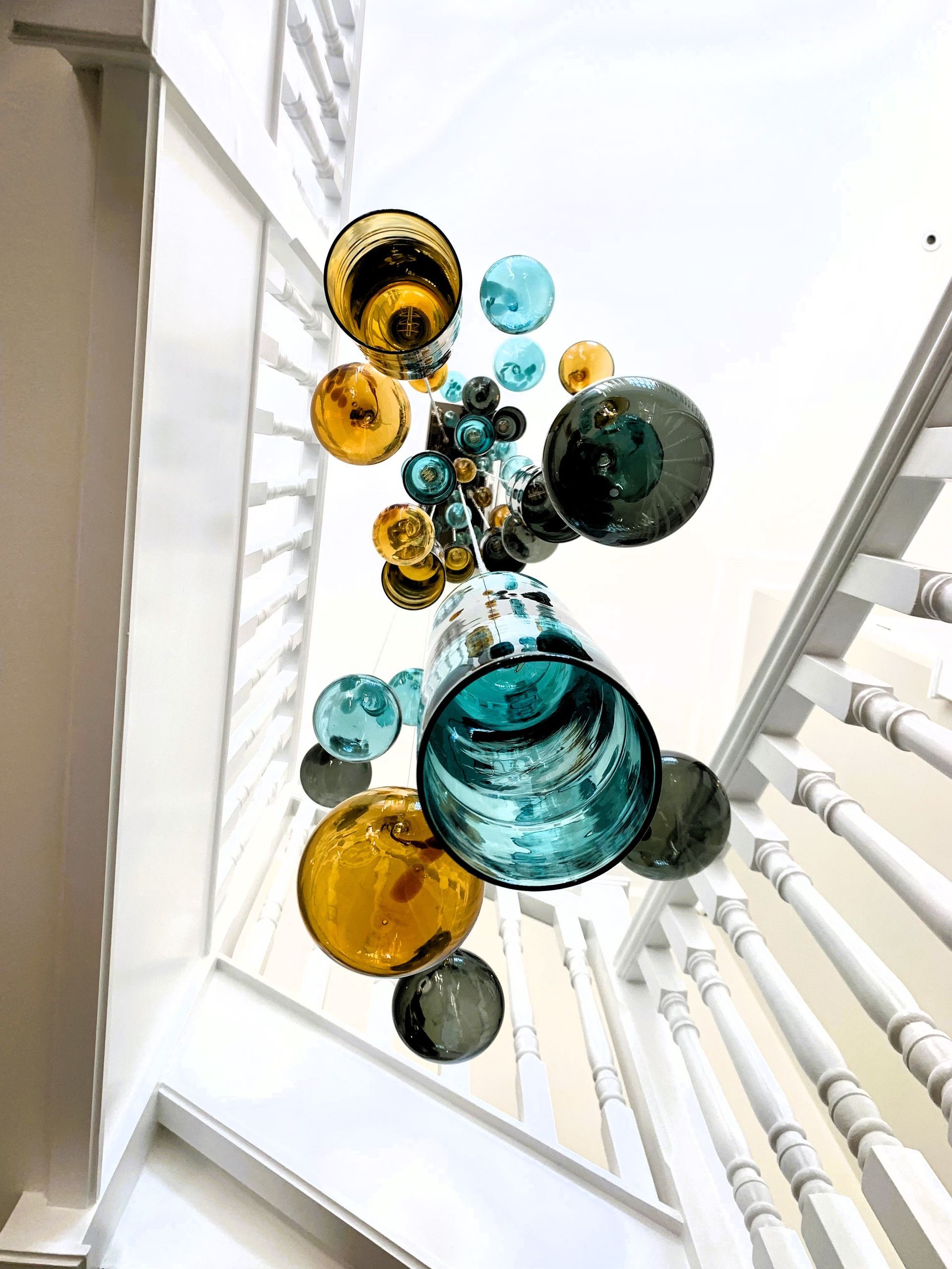 a staircase with a glass ball chandelier by Roast Designs hanging from the ceiling