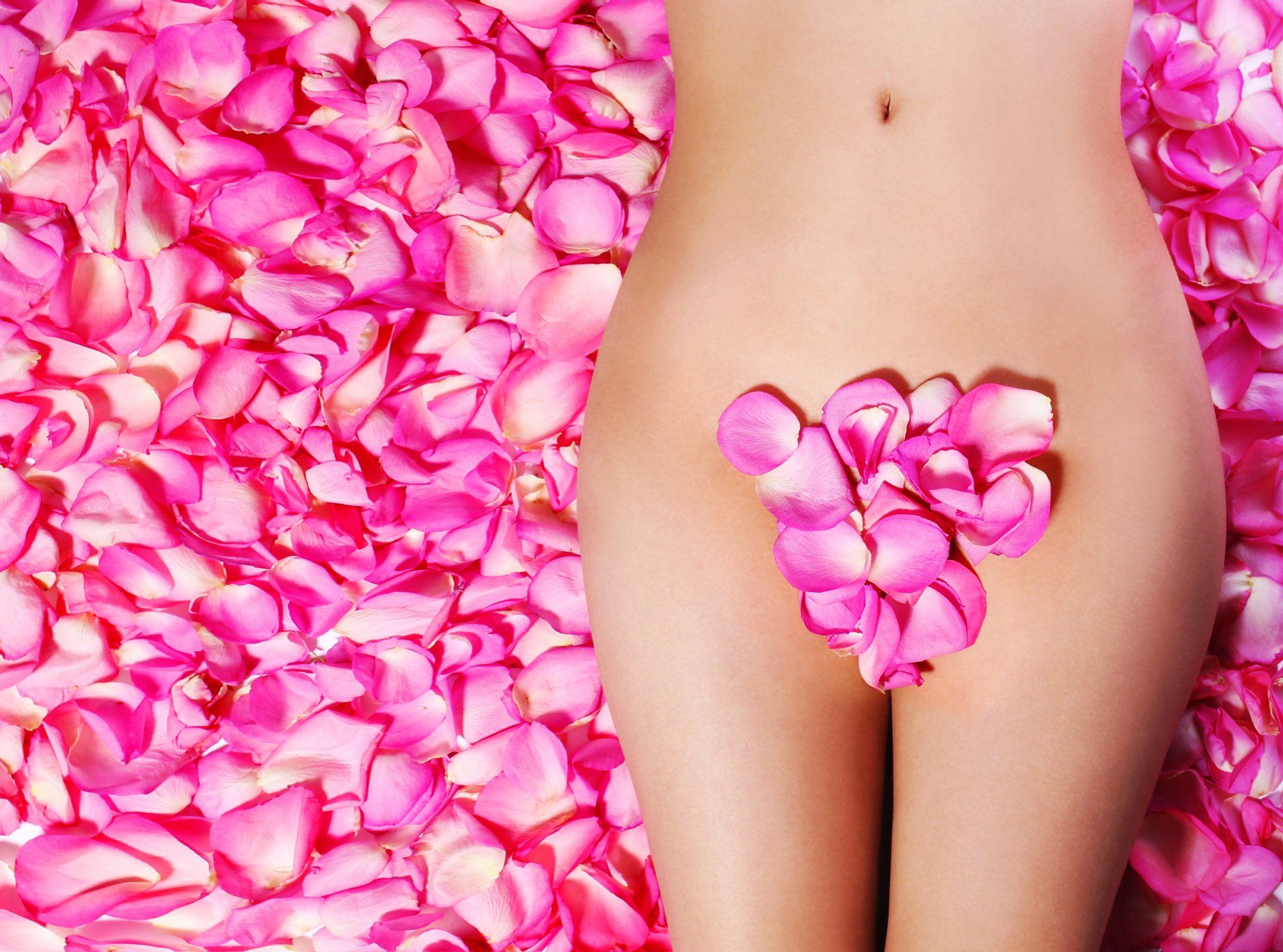 A woman laying on a bed of pink petals with a selection covering her delicately