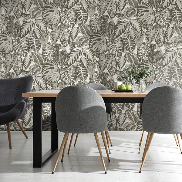 a dining room with a table and chairs in front of a wall with leaves on it